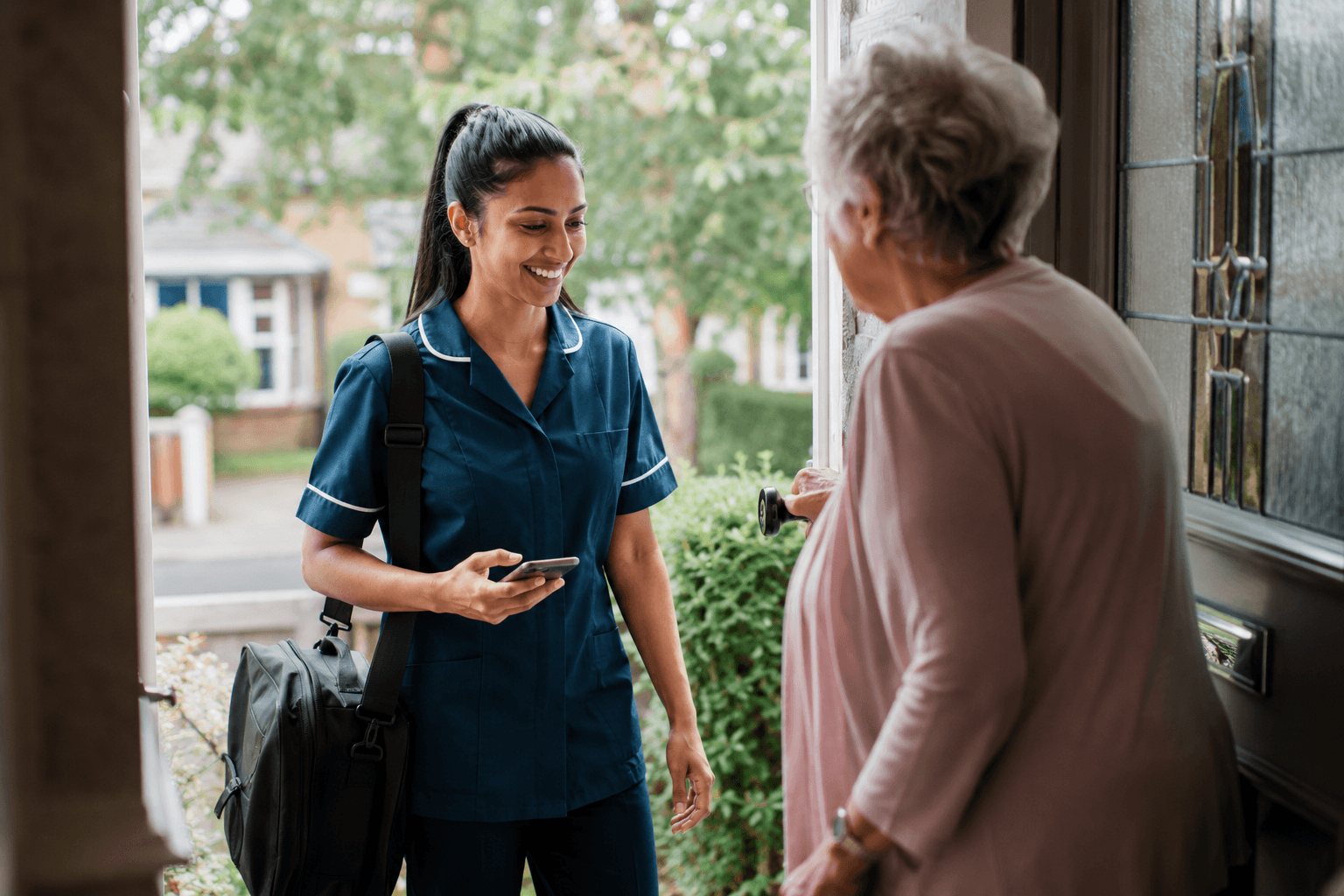 A visiting nurse talking with an older person at their front door